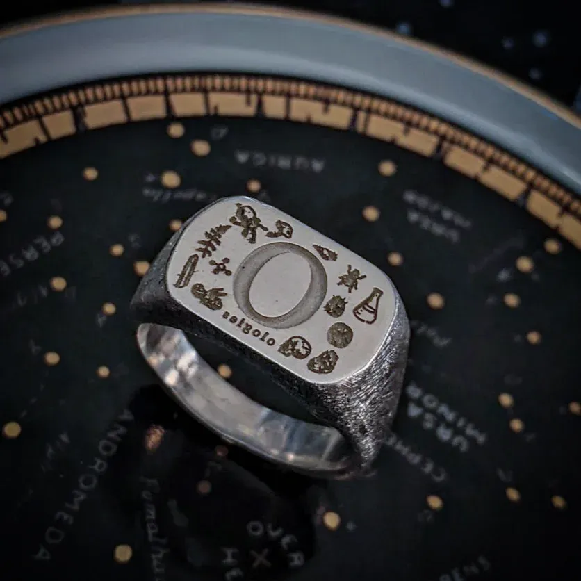 A photo of the Ologies signet right. It features a simplified version of the illustrations in the logo, surrounding an 'O'